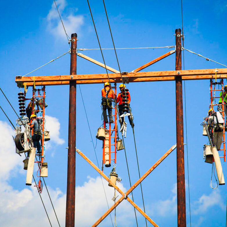 Six ͵ Group employees elevated in the sky to work on transmission lines